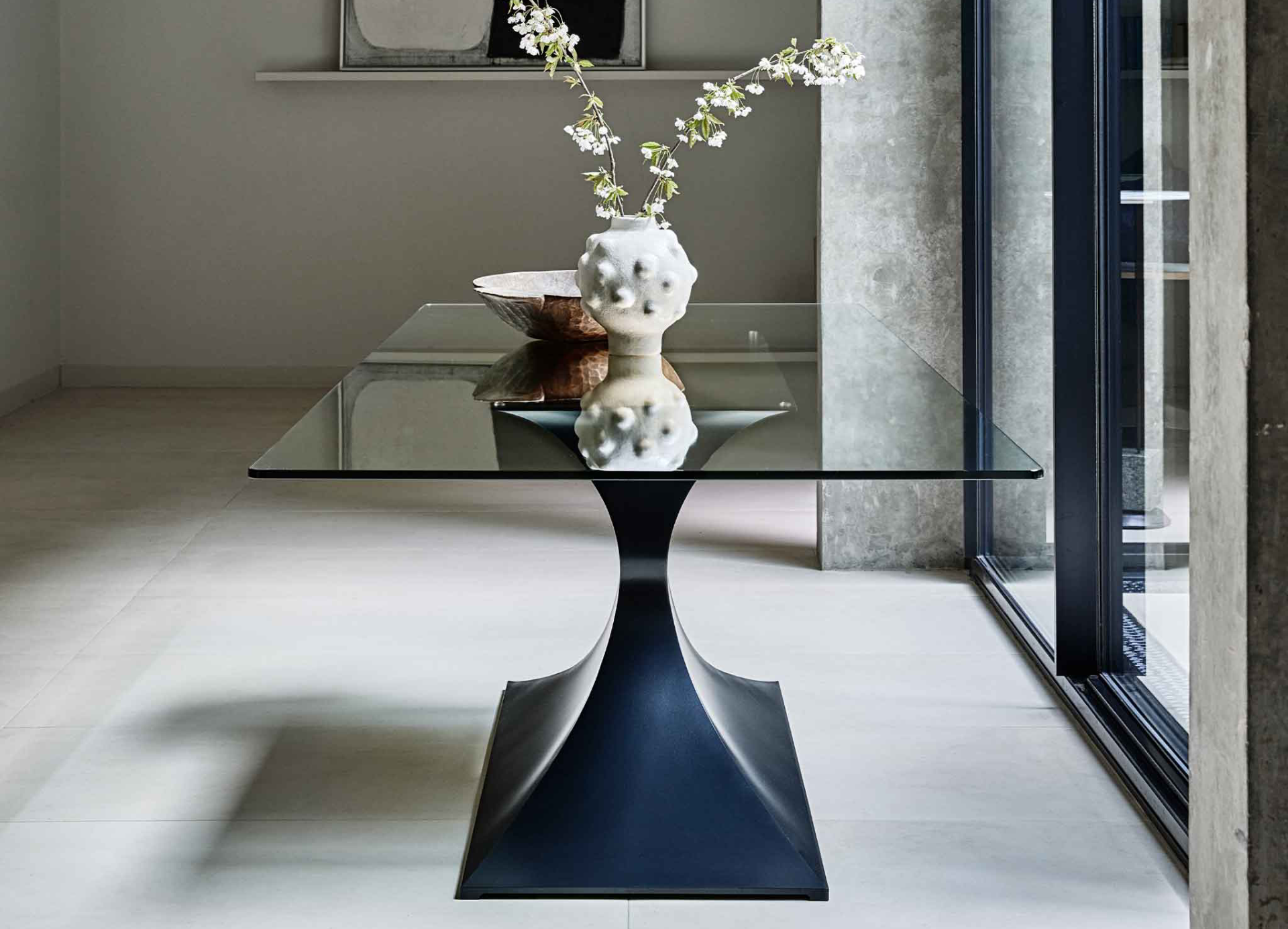 A modern metal and glass dining table on a natural stone floor