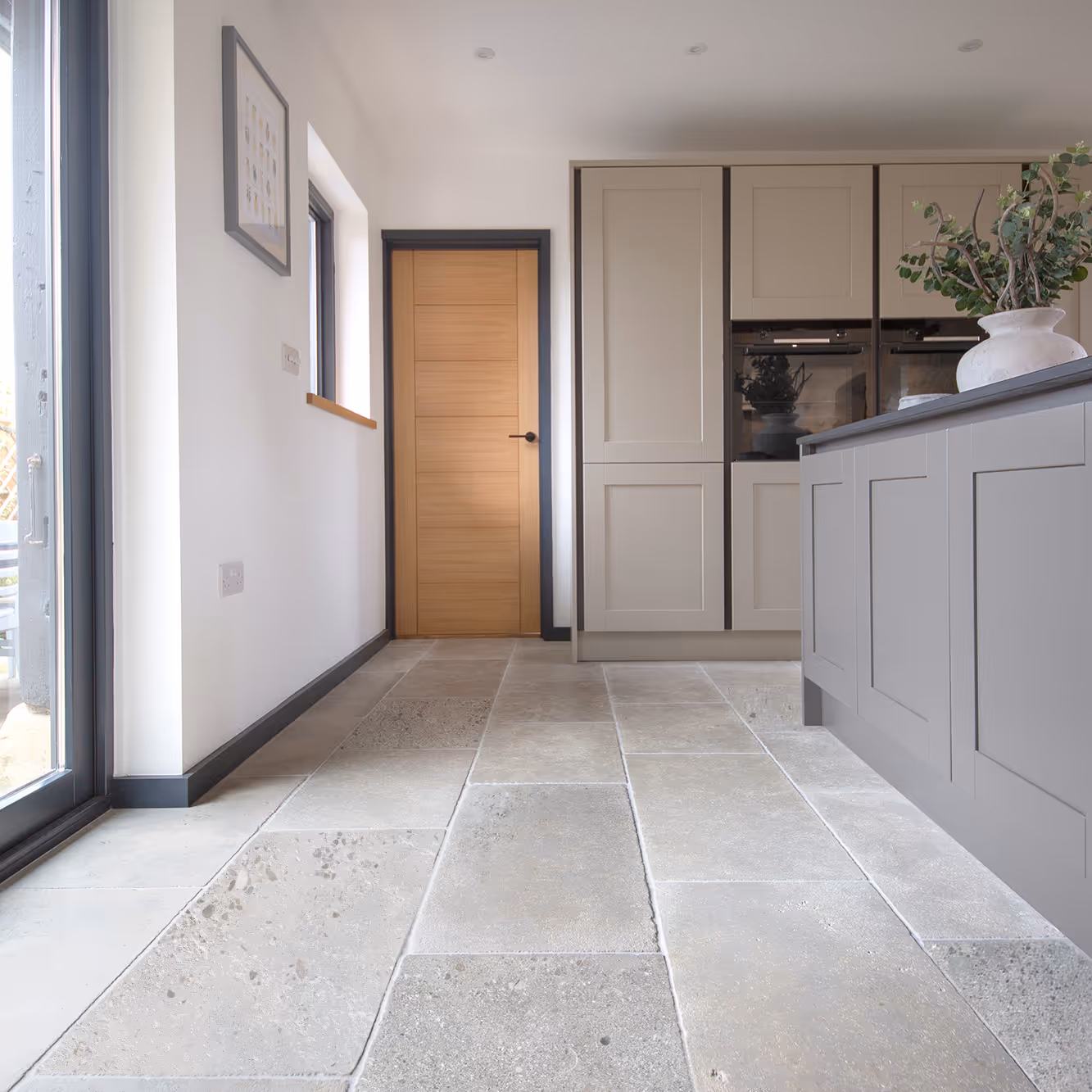 A grey shaker kitchen with a natural limestone floor.
