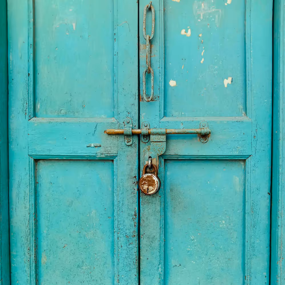 A bright turquoise door with peeling paintwork.