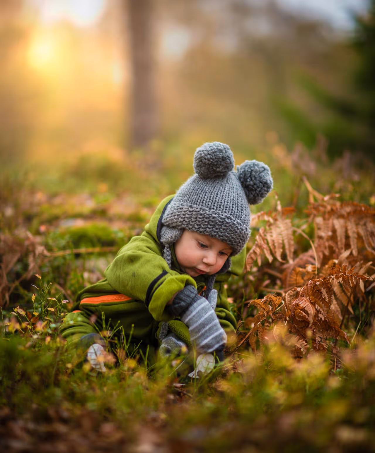 A young boy discovering the joy of leaves and moss on a forest floor.