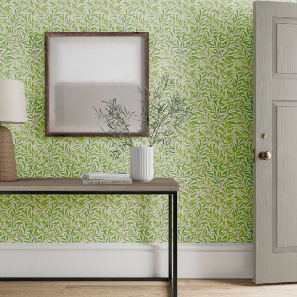 A modern metal console table in front of a wallpaper in a green leaf design.