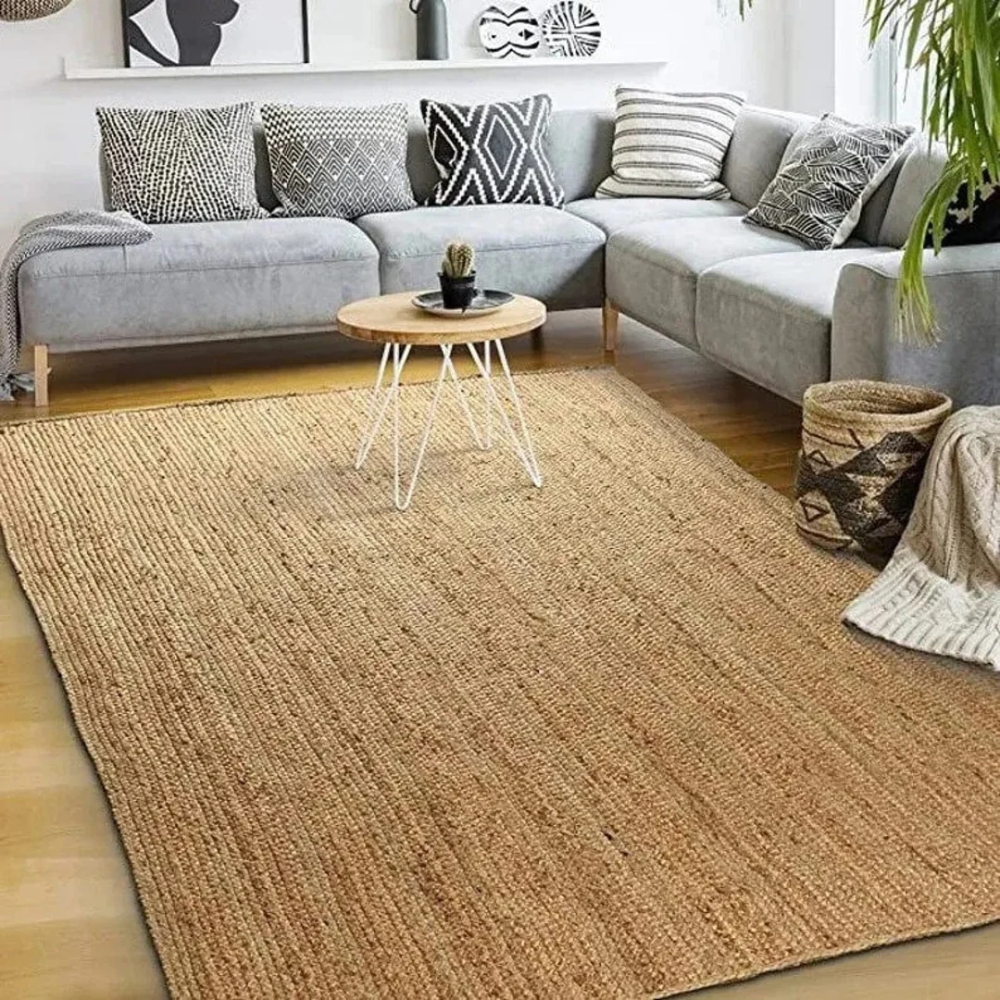 A modern white room with a pale grey corner sofa and a natural jute rug on a wooden floor.