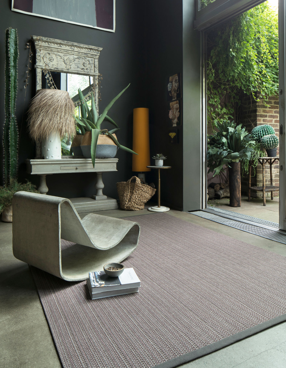 A masculine feeling room with a natural rug and an eclectic mix of furniture, and doors opening out into the garden.
