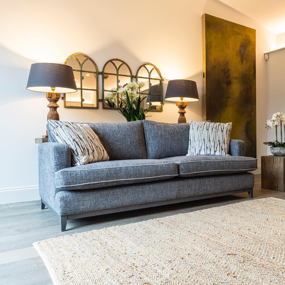 A grey upholstered sofa in a neutral decorated room.