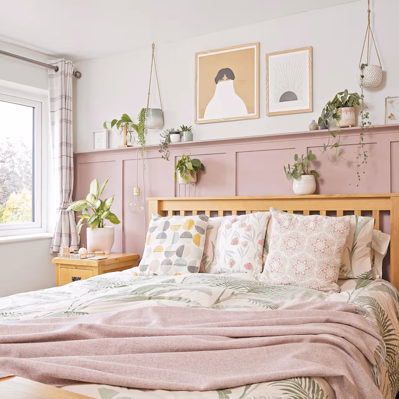 A pretty bedroom with pink panelling behind the bed