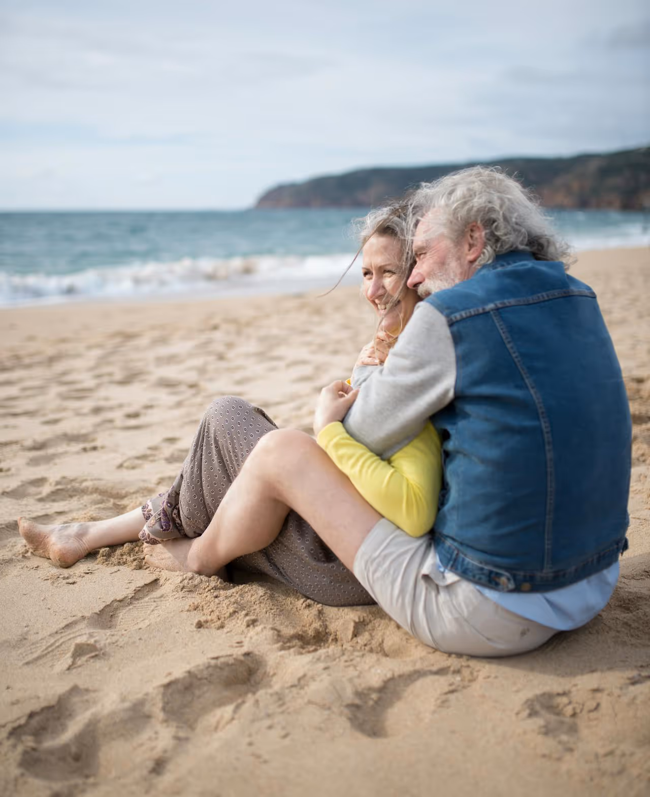 A couple sitting on a sandy beach admiring the waves