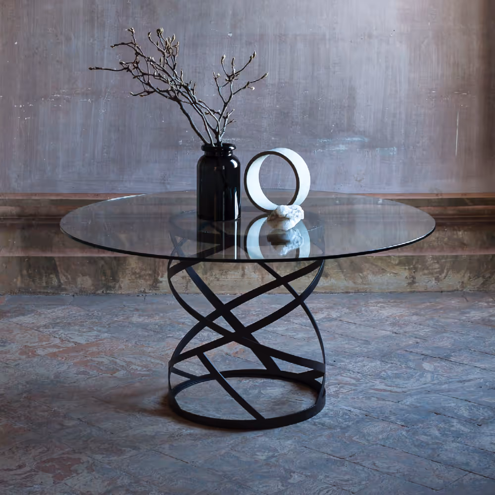 A lifestyle photo of a handmade metal and glass round table sitting in a dilapidated house.