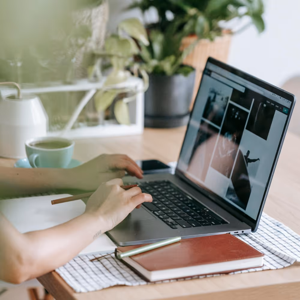 A person sat at a table typing on a laptop