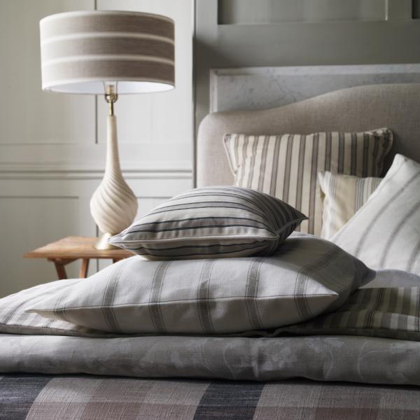 Grey and neutral cushions on a bed