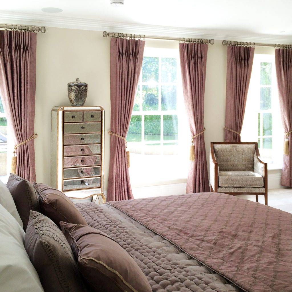 Large bedroom with antique mauve silk curtains and a large bed with mauve silk bedspread and white fine cotton linen