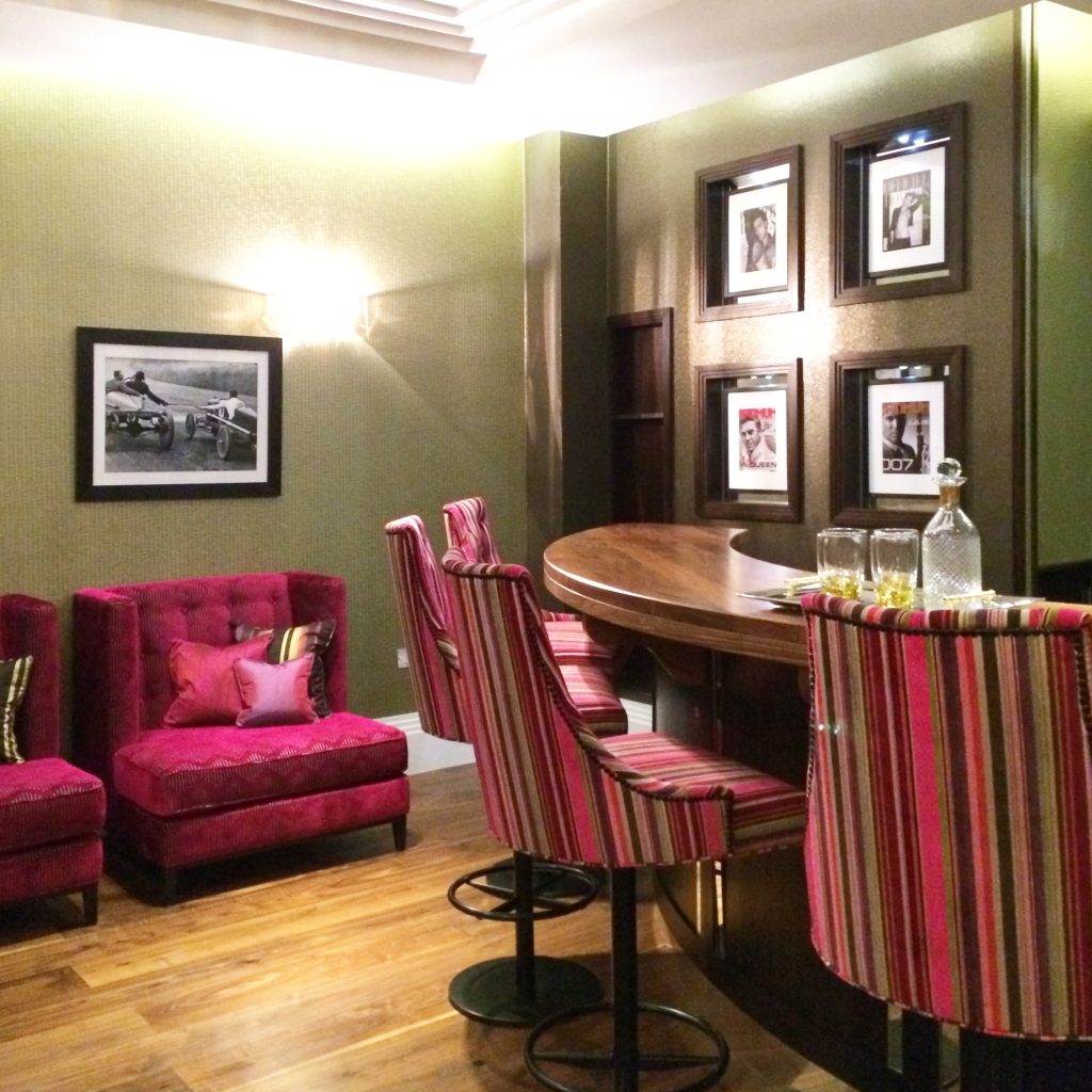 Elegant home bar with fuchsia pink velvet upholstered chairs and bar stools in fuchsia pink and green stripe velvet
