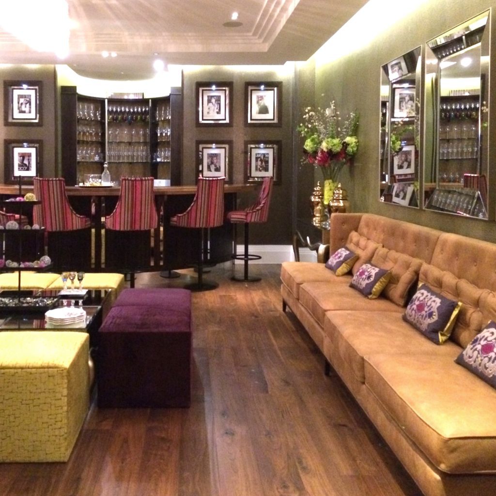 Large entertaining room of a mansion with fitted bar, upholstery bar stools and leather and velvet sofas