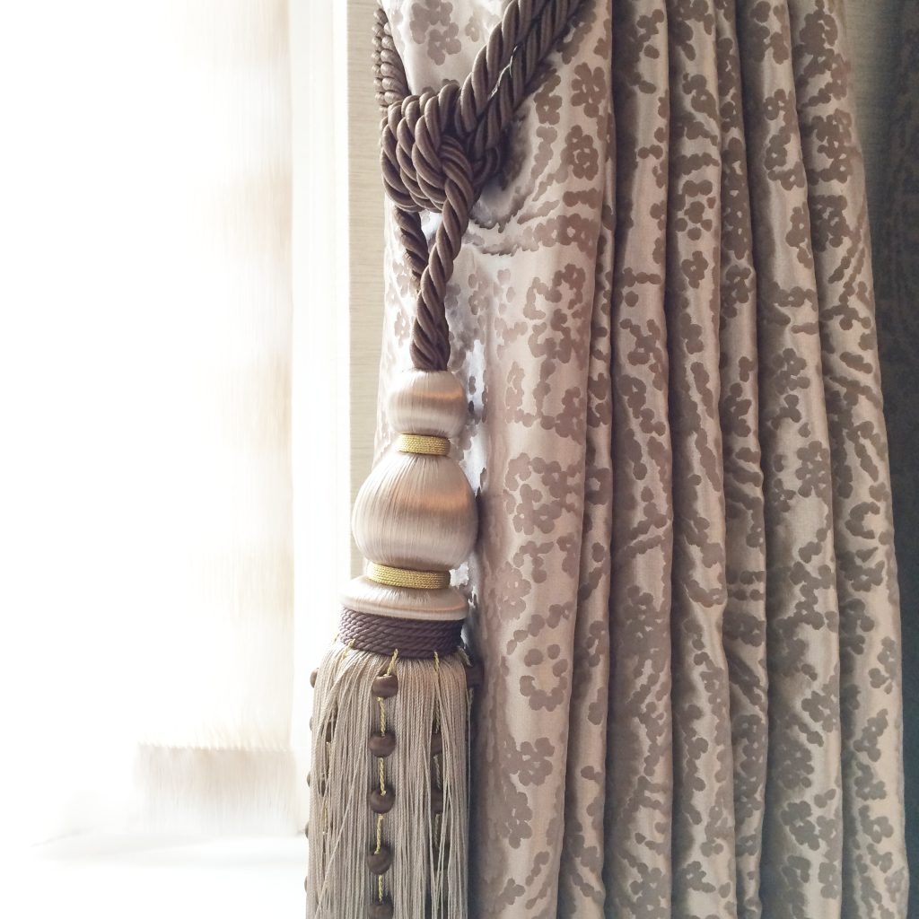 Close up of patterned silk curtains and tassel tiebacks in a dusty mauve colourway 