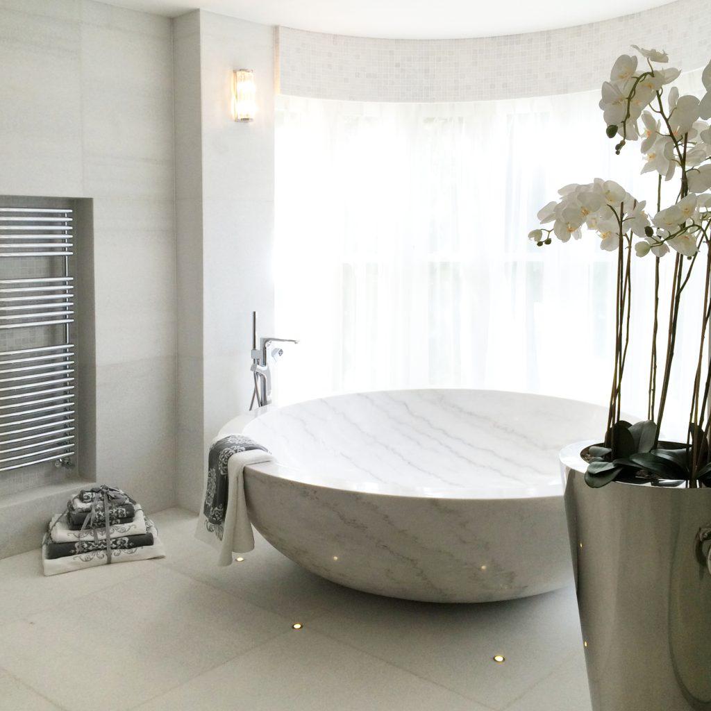 Large white solid marble round bath and freestanding chrome taps