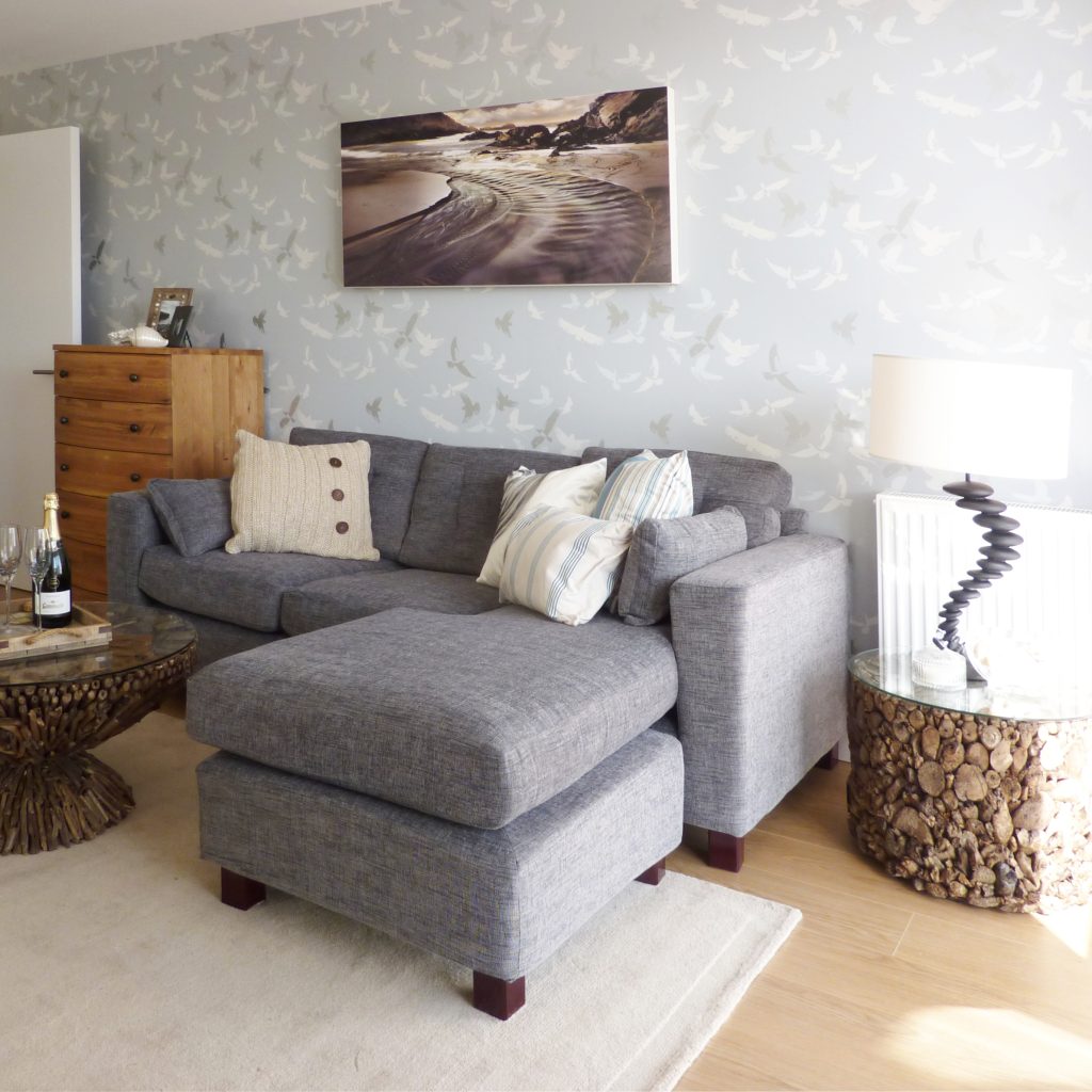 Coastal themed living room with a grey corner sofa and reclaimed driftwood table