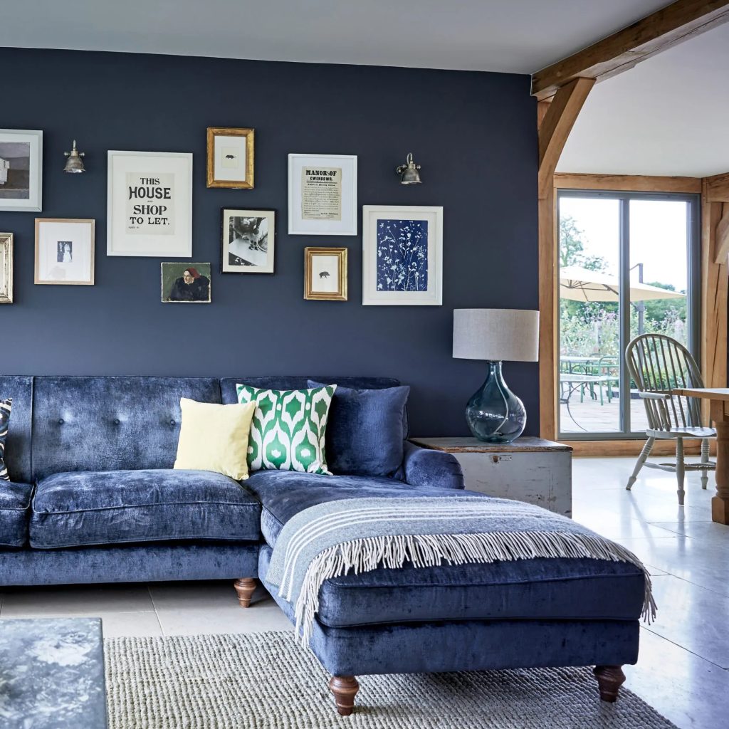 Blue velvet corner sofa against a blue painted wall