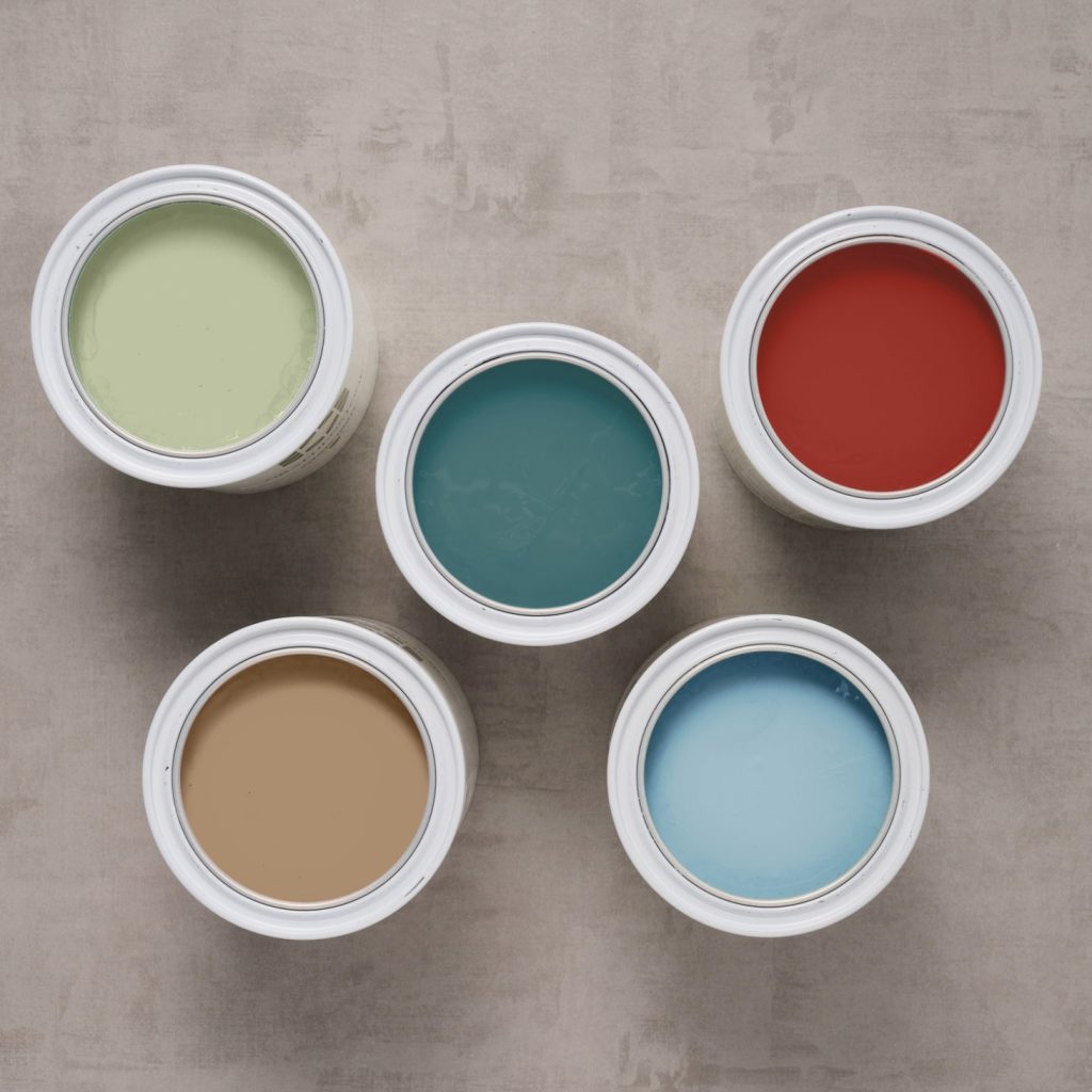 Tins of emulsion paint in pale green, teal, terracotta, sandstone and light blue.
