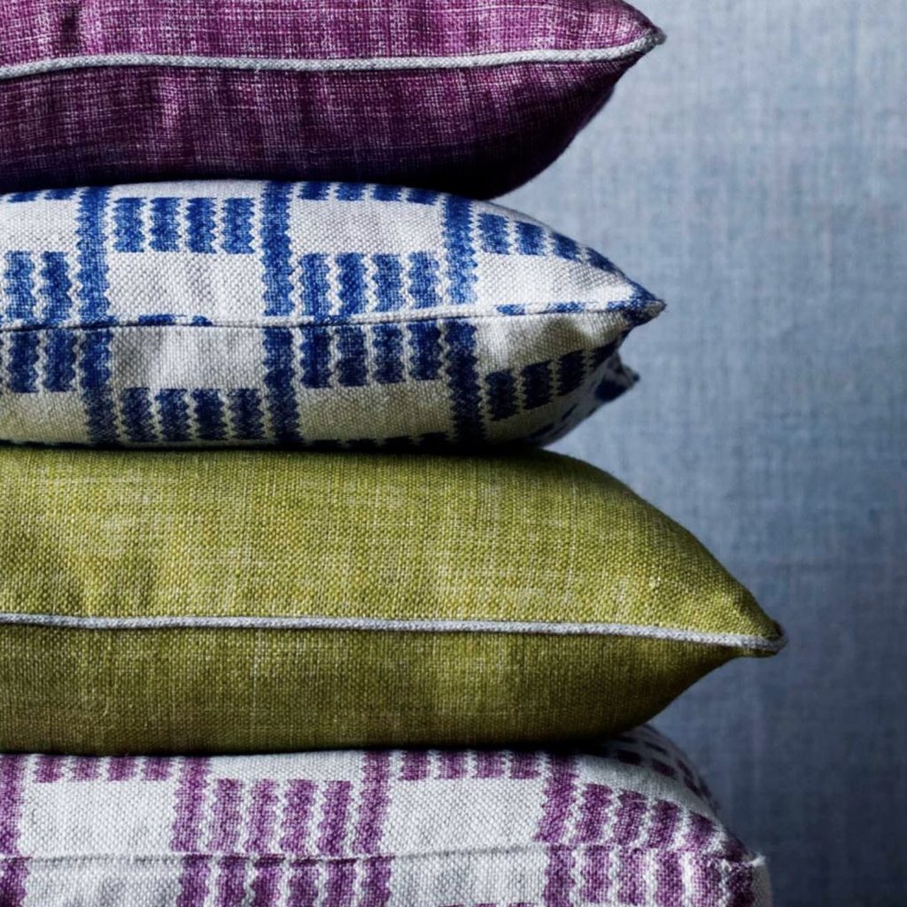 A stack of cushions in purple, blue and green organic cotton