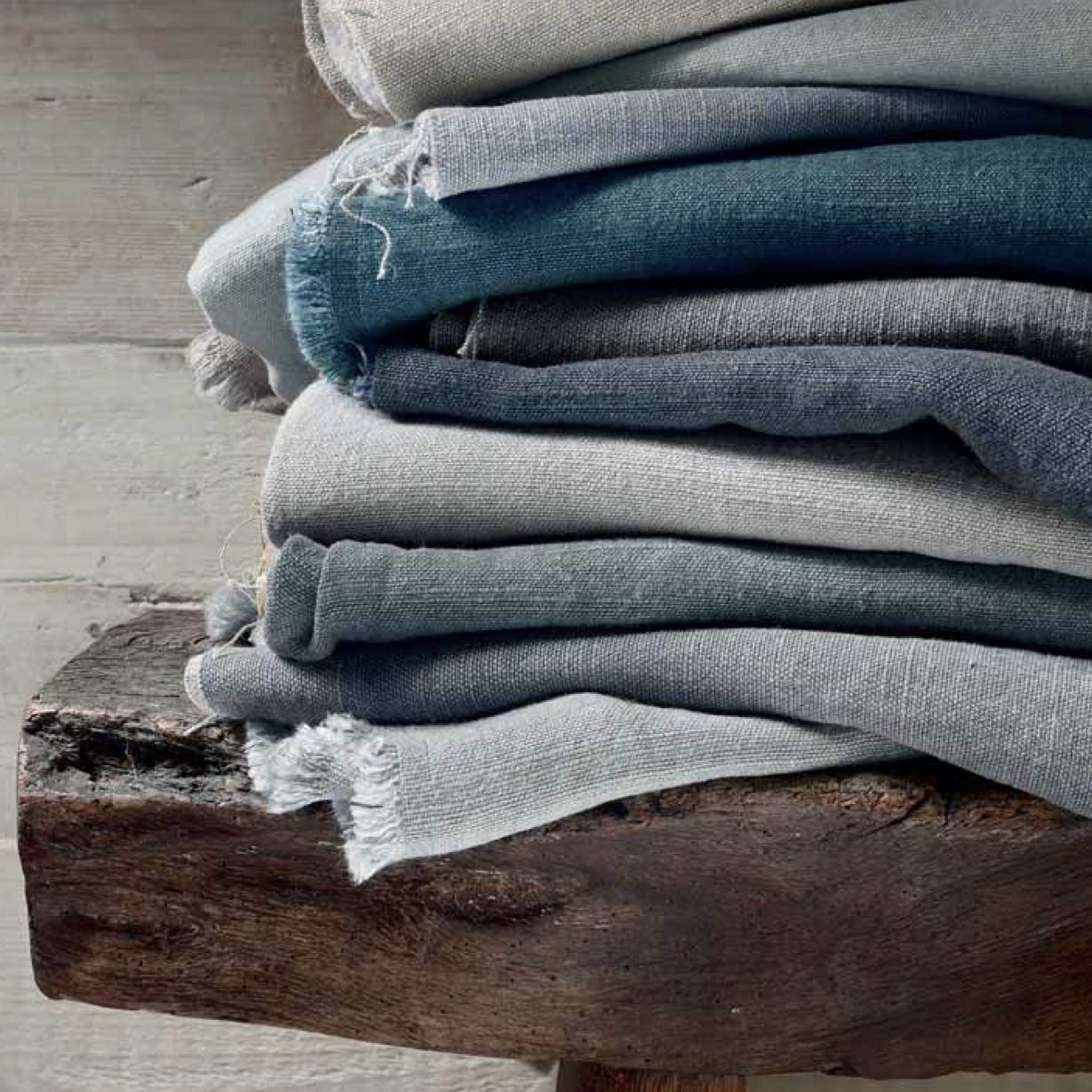Stack of fine linen cloth samples in various shades of blue and natural