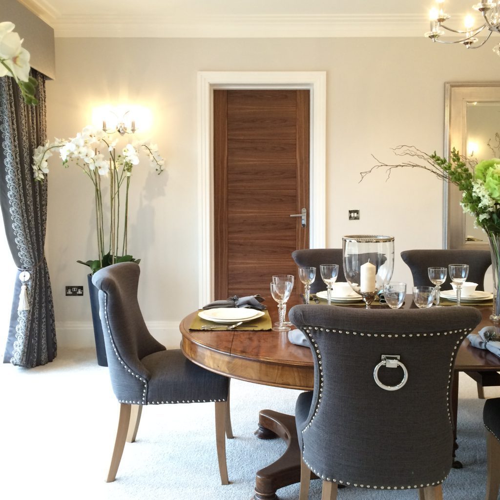 Elegant dining room with large scale antique walnut dining table and grey upholstered chairs