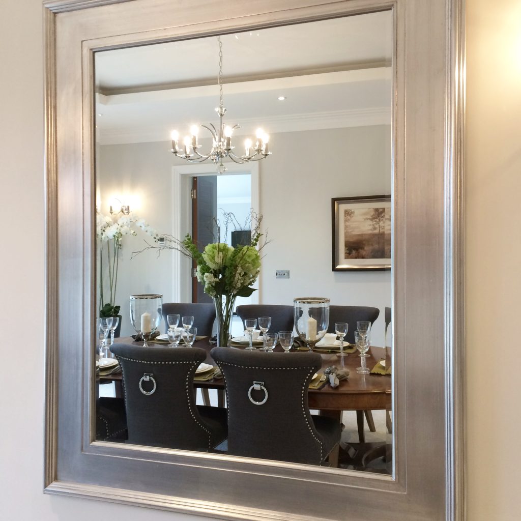 A silver framed mirror, reflecting the dining room beyond