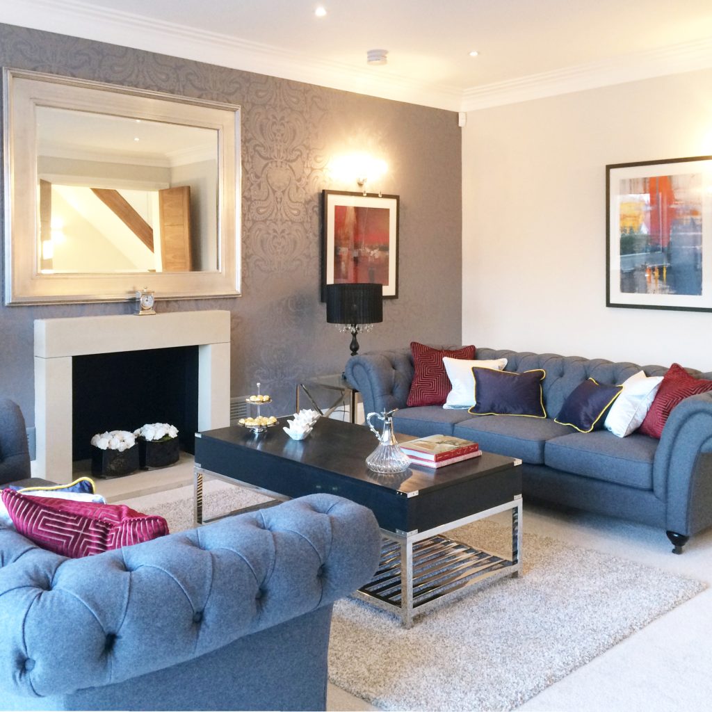 Drawing room in blue-mauve decoration with grey sofas and red cushions