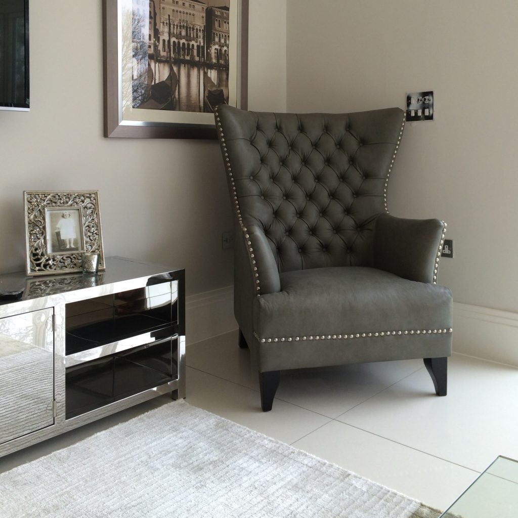 Dark taupe leather wing chair and a polished stainless steel low TV unit
