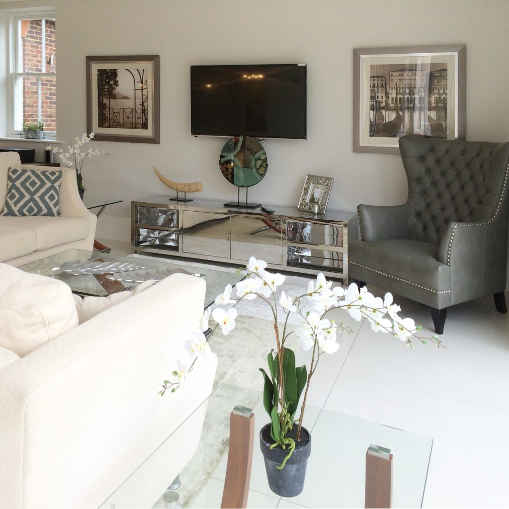 Family room with a taupe leather wing chair, stainless steel TV unit and cream corner seating