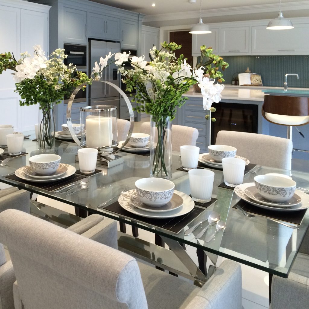 Glass and stainless steel dining table with pale grey dining chairs