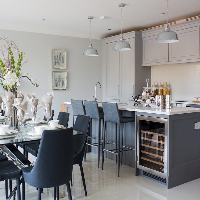 Grey painted shaker kitchen with glass dining table and grey upholstered chairs