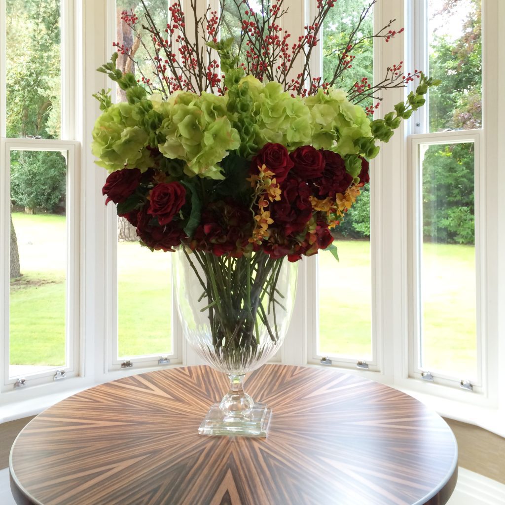 Large glass vase of flowers on a zebrano wood round table