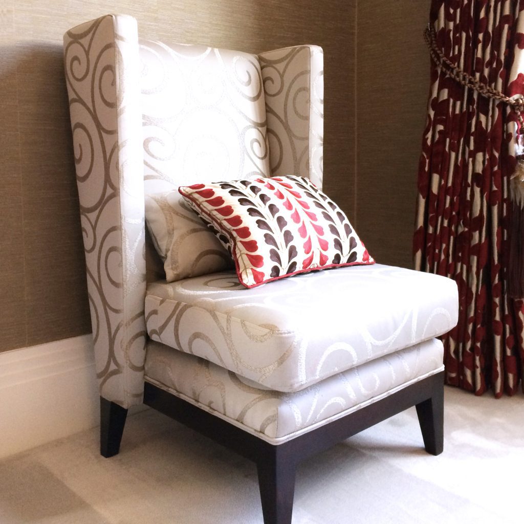 Elegant wing chair in cream with red and gold curtains