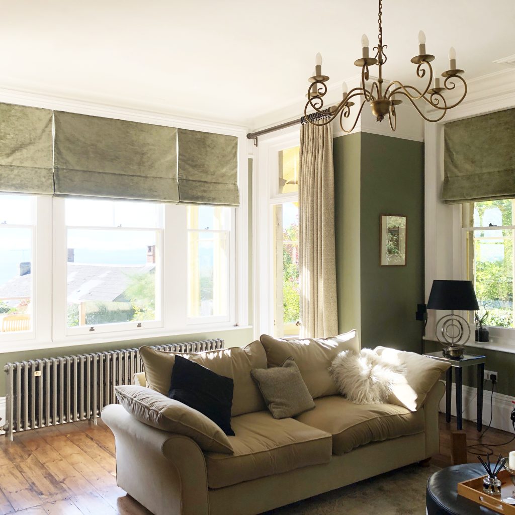 Elegant drawing room with khaki green walls and window furnishings