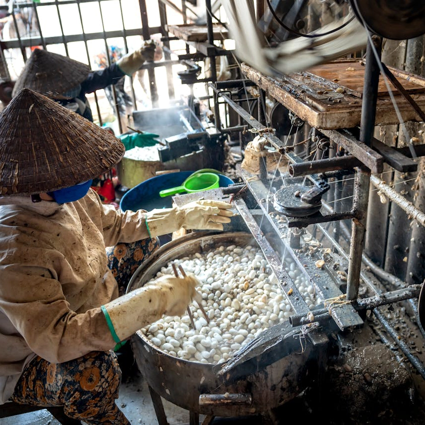Two ladies working in an old and dirty silkworm factory