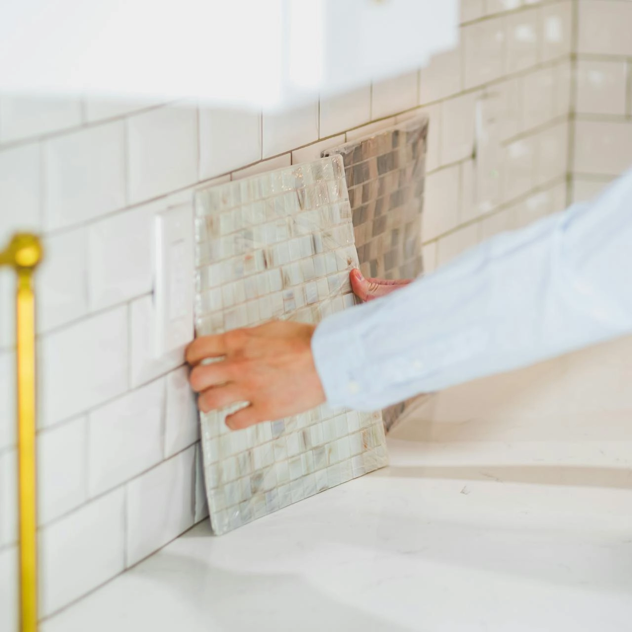 A lady deciding on wall tiles in a kitchen