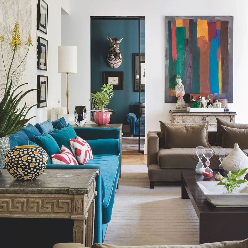 An eclectic mix of modern and antique furniture in this white room with a strong teal sofa