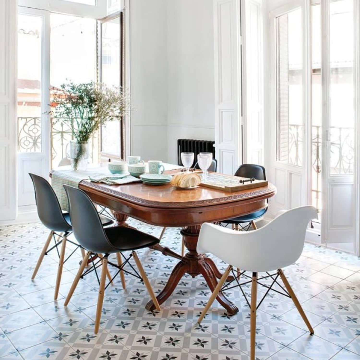 A white room with a dark wood antique dining table and modern plastic dining chairs