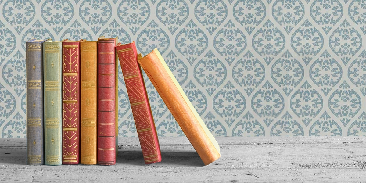 Old books sat against a blue white wallpaper