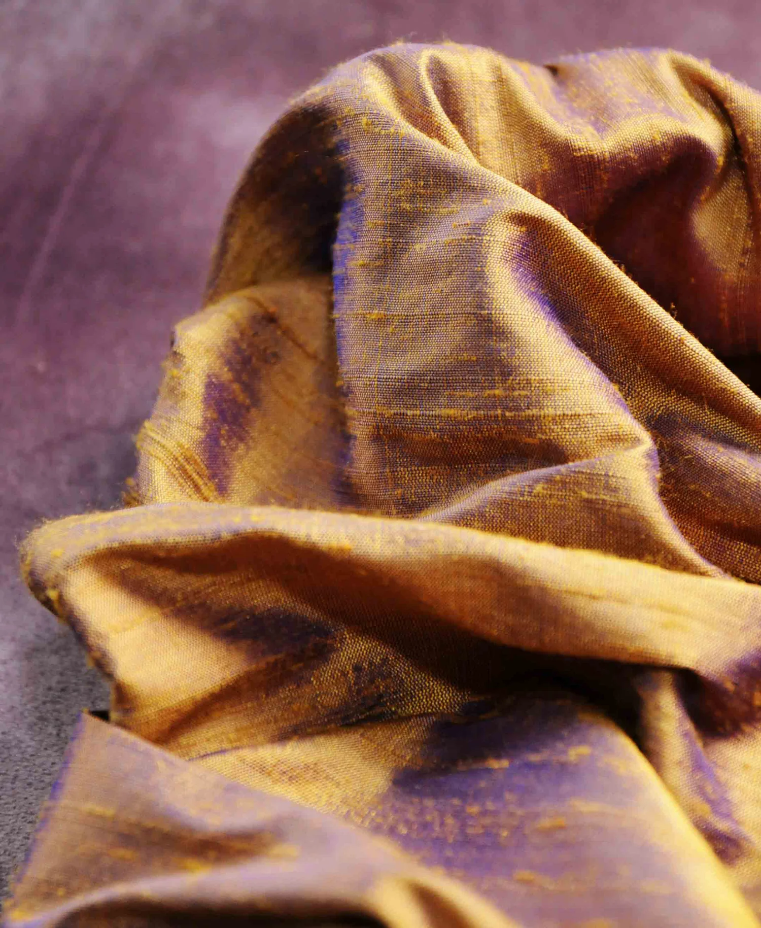 A scrunched up sample of duping silk in a bronze lilac colour