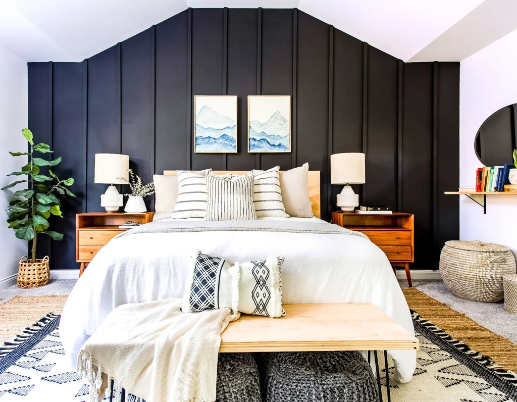 A white bedroom with a black panelled wall behind the bed