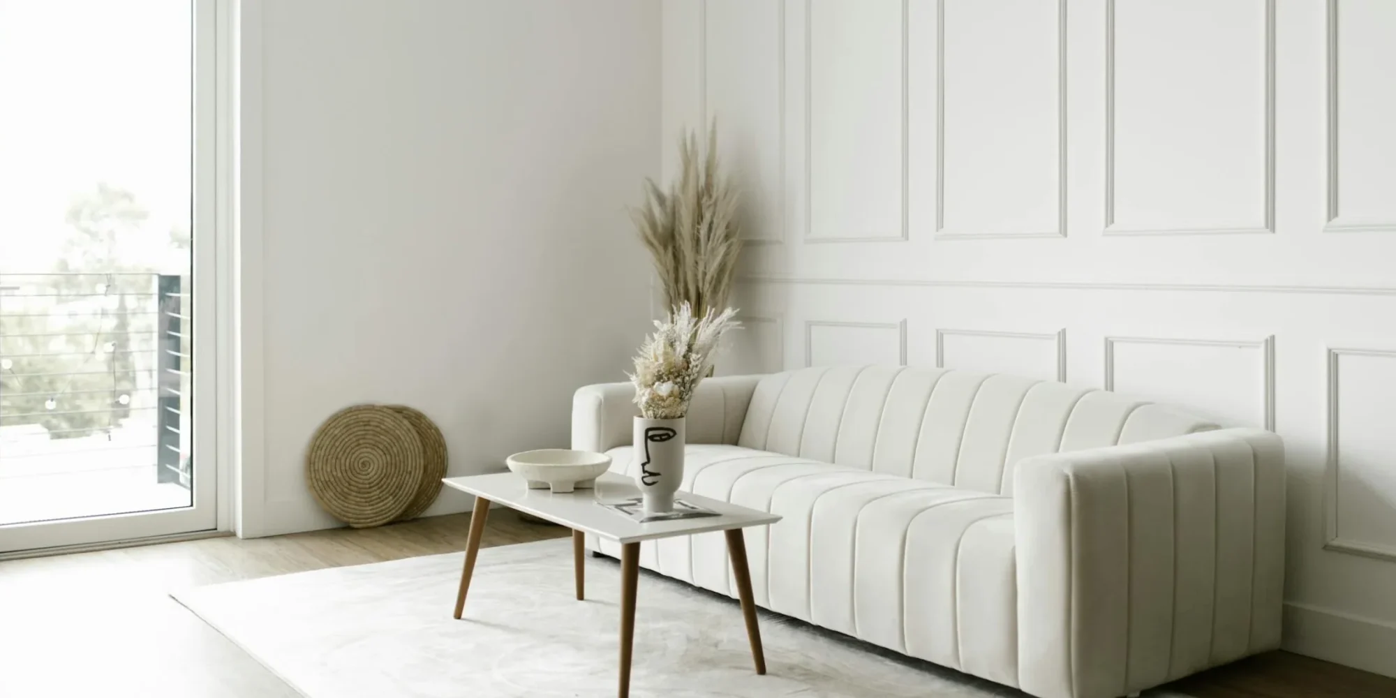 A living room with white walls, white rug and white furniture