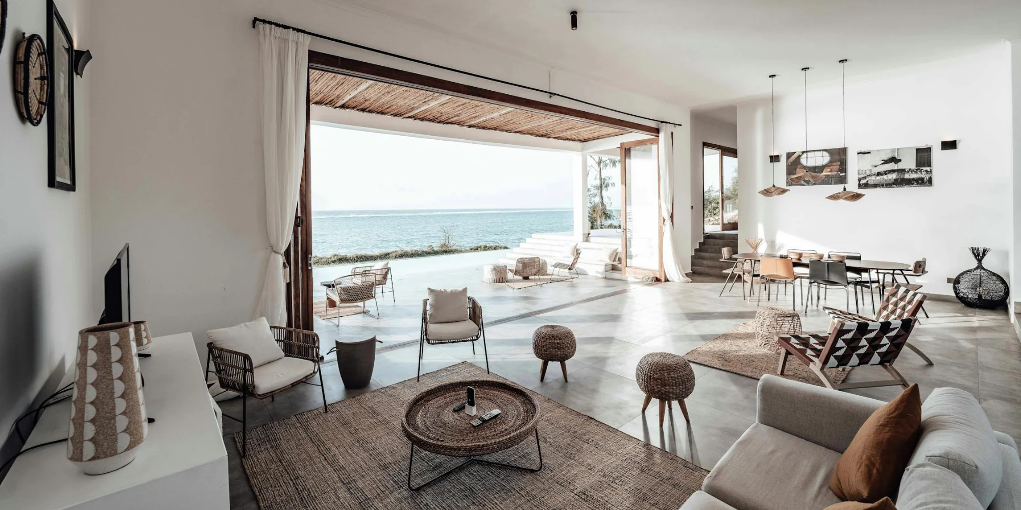 A spacious living room with bi-fold doors opening out to a patio facing the sea