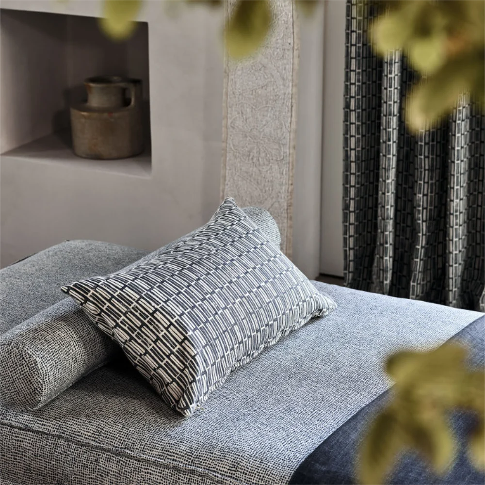 A modern day bed in grey fabric with scatter cushion and bolster cushion