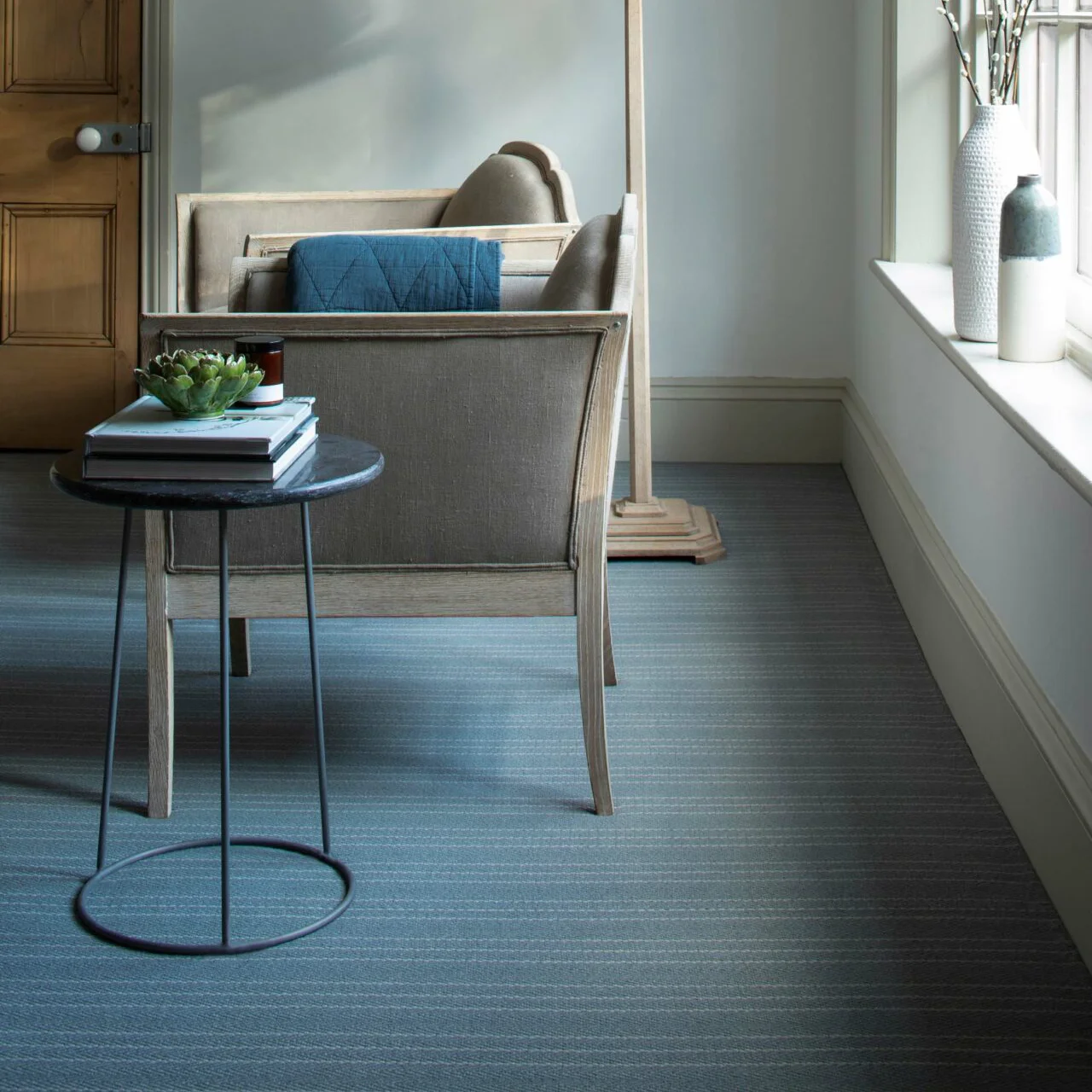 A blue striped carpet with a wooden sofa and small side table